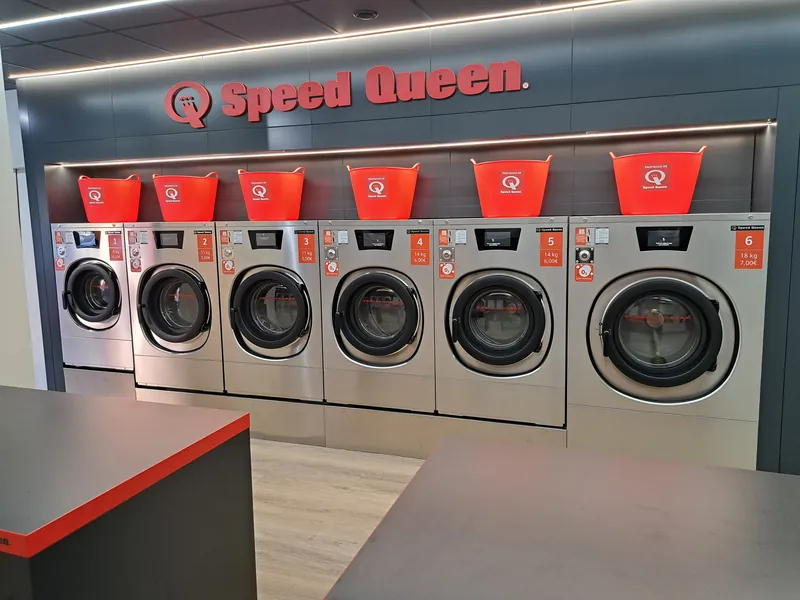 Sala de lavado, con lavadoras Speed Queen y mesas de plegado · Lavandería Gira Gira en Villa de Vallecas