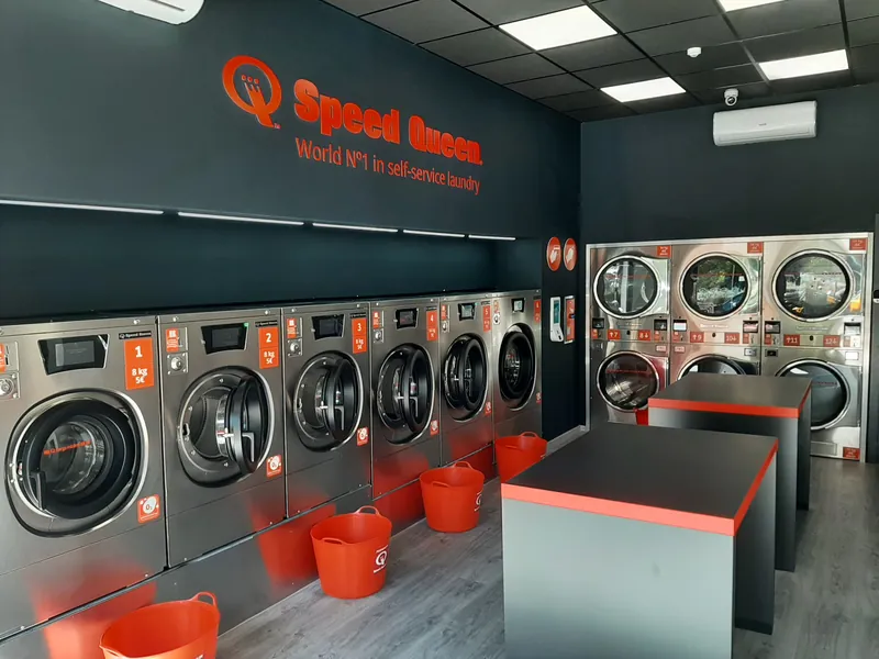 Sala de lavado, con lavadoras Speed Queen y mesas de plegado · Lavandería Gira Gira en Vicálvaro